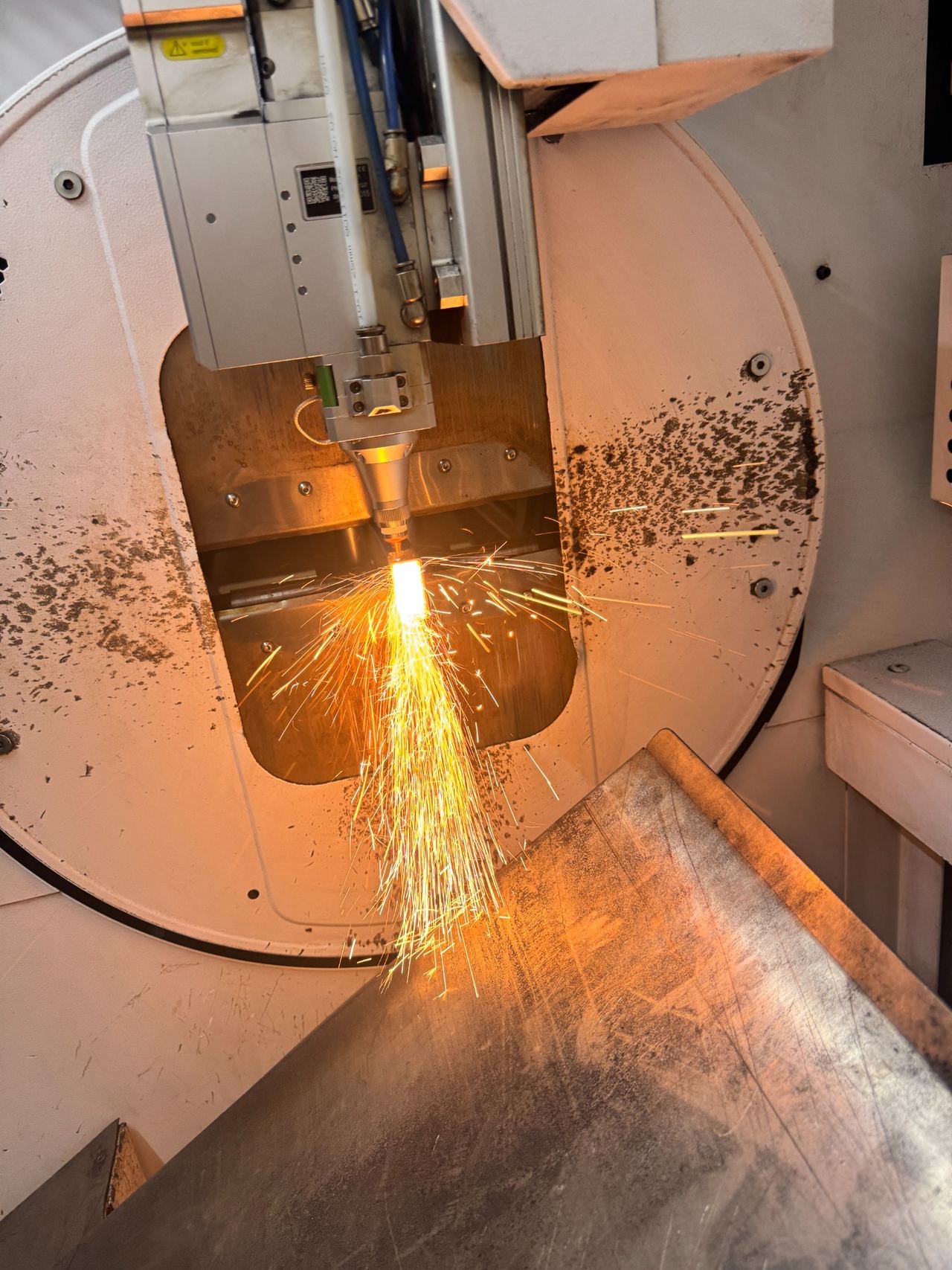De profiellasersnijmachine van Vakstaal in actie, met vonken tijdens het snijden van metaal.